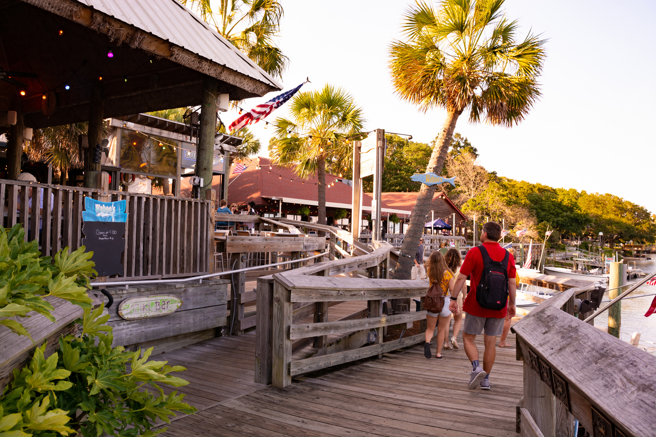 People enjoying time on vacation in South Carolina. The MarshWalk, located in historic fishing village. People walking on wooden boardwalk on the marsh next to restaurants, bars and boats.